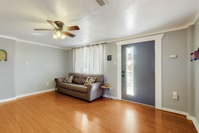 living area with a textured ceiling, light wood-type flooring, visible vents, and baseboards