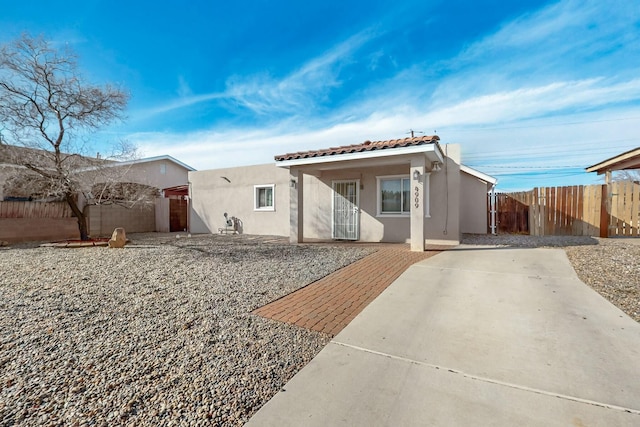 view of front facade featuring a patio area, a tiled roof, fence, and stucco siding