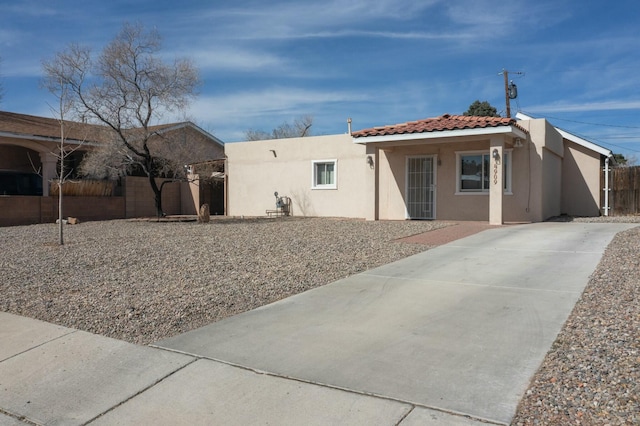 view of front of house featuring a tiled roof, fence, and stucco siding