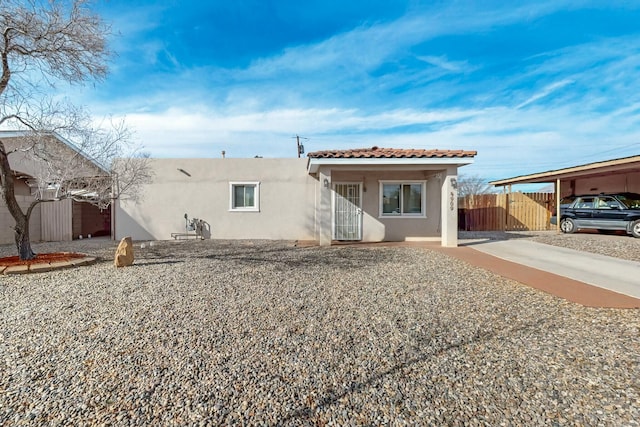 view of front facade featuring a tiled roof, fence, and stucco siding