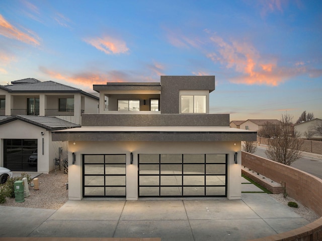 contemporary home with concrete driveway, a balcony, and stucco siding