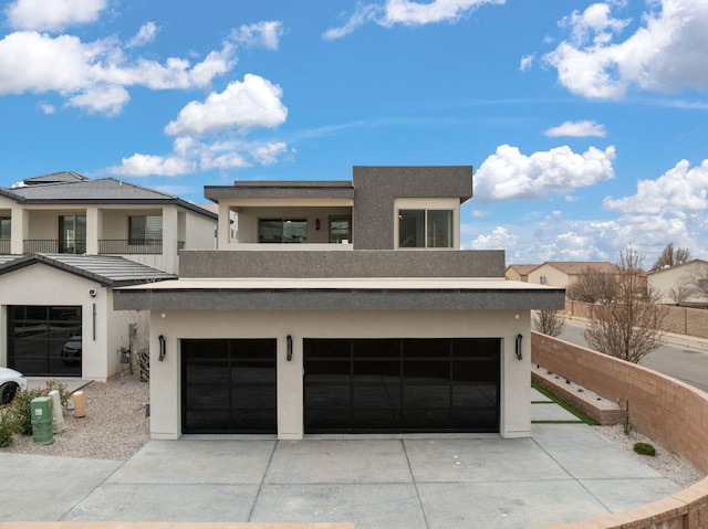 view of front of house with concrete driveway, a balcony, and stucco siding