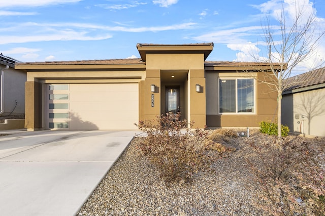 view of front facade with stucco siding, a garage, and driveway