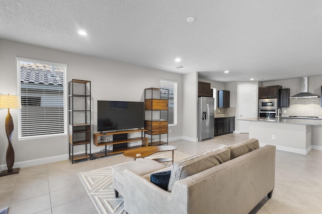 living room featuring light tile patterned floors, recessed lighting, baseboards, and a textured ceiling