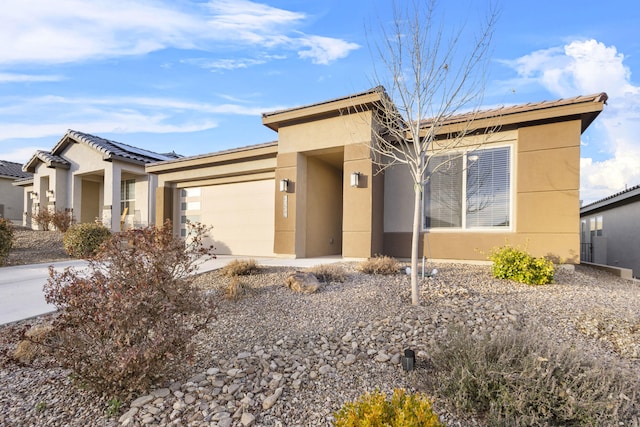 view of front of house with concrete driveway, a garage, roof mounted solar panels, and stucco siding