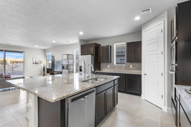 kitchen with visible vents, a kitchen island with sink, a sink, appliances with stainless steel finishes, and open floor plan