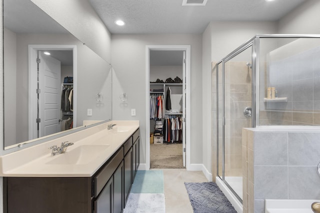 full bathroom featuring a sink, a spacious closet, double vanity, and a shower stall