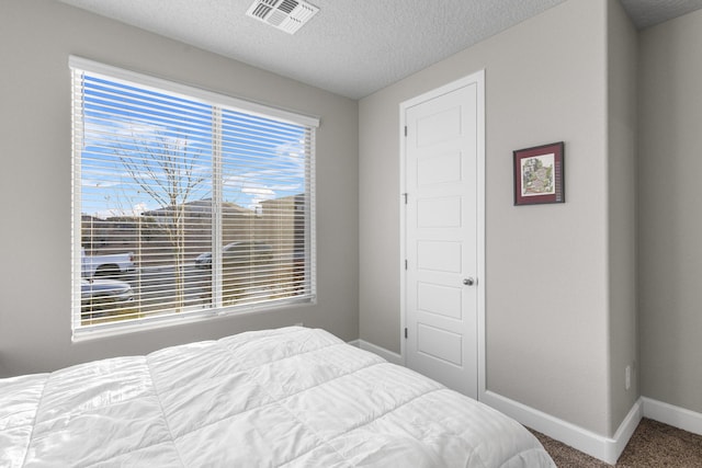 carpeted bedroom featuring baseboards, visible vents, and a textured ceiling