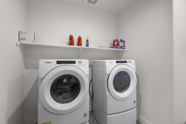 clothes washing area with laundry area, washer and dryer, and baseboards