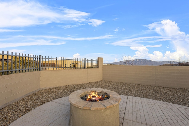 view of patio with a fenced backyard, a mountain view, and a fire pit