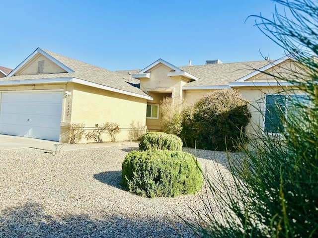 view of front facade with an attached garage, driveway, roof with shingles, and stucco siding