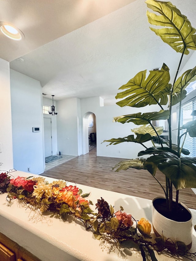 interior space featuring a textured ceiling, arched walkways, and wood finished floors