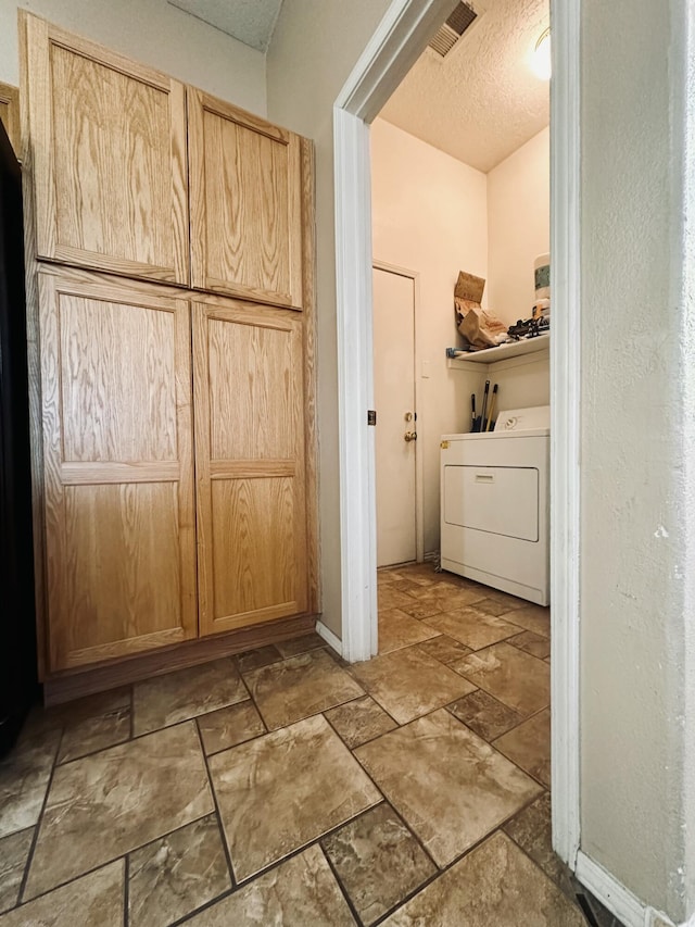 washroom featuring washer / clothes dryer, visible vents, stone finish floor, a textured ceiling, and laundry area