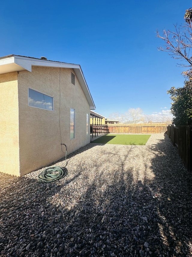 view of side of property with a patio, a fenced backyard, and stucco siding