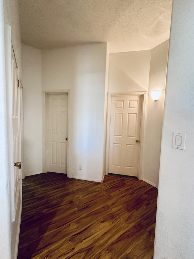 hallway with dark wood-style floors and a textured ceiling