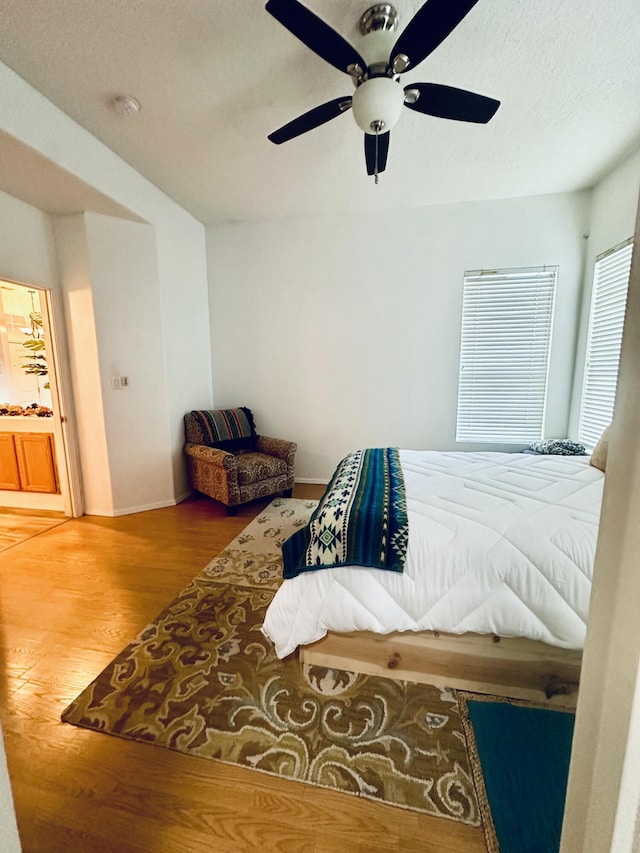 bedroom featuring baseboards, a textured ceiling, a ceiling fan, and wood finished floors