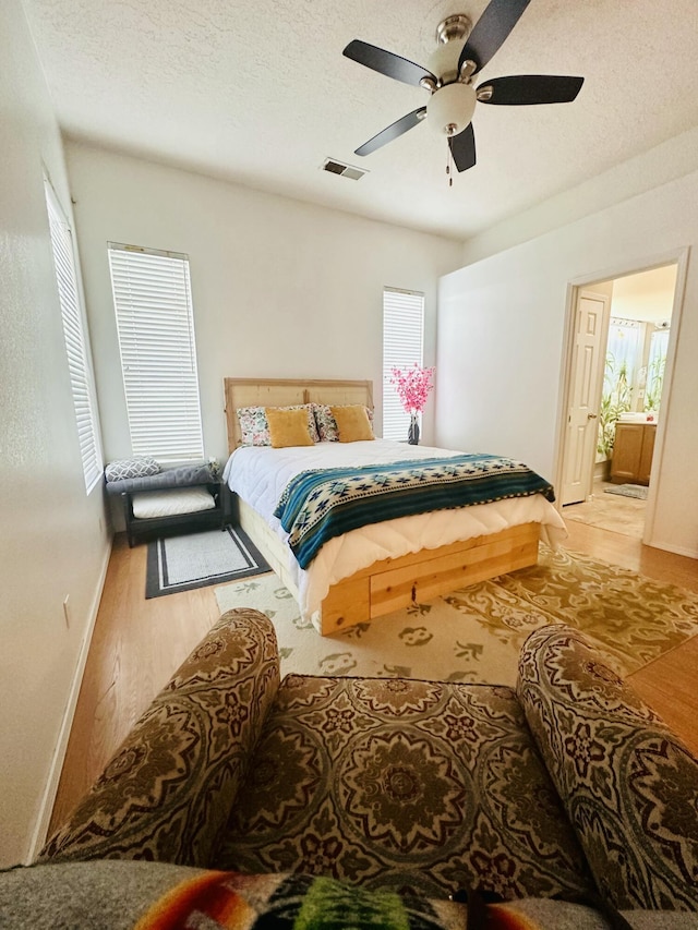 bedroom with a textured ceiling, visible vents, and wood finished floors