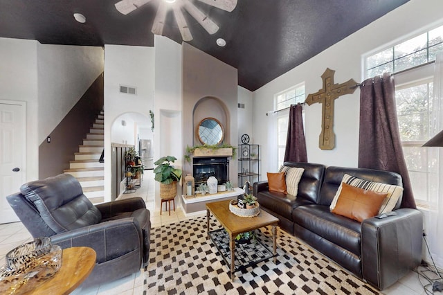 tiled living area with a high end fireplace, visible vents, a healthy amount of sunlight, and stairway