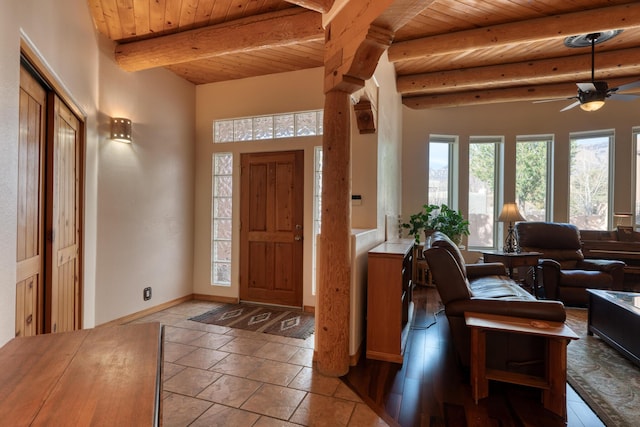 foyer entrance with wooden ceiling, a ceiling fan, baseboards, beamed ceiling, and stone tile flooring