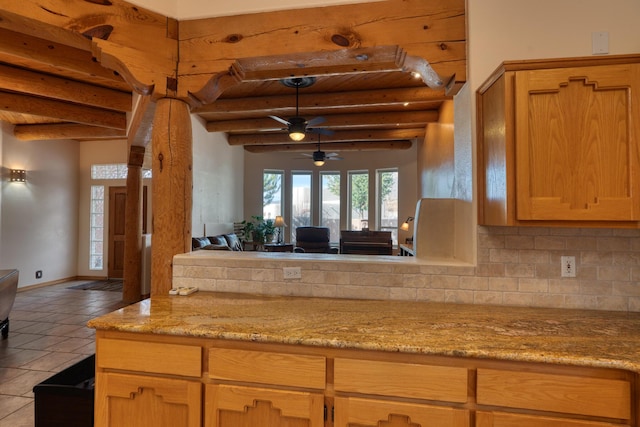 kitchen featuring light tile patterned floors, open floor plan, beamed ceiling, light stone countertops, and backsplash