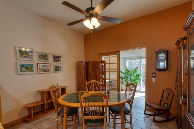 dining area featuring ceiling fan, stone tile flooring, and baseboards