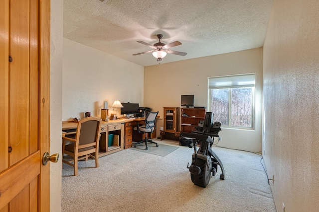 home office featuring carpet floors, a textured wall, a textured ceiling, and a ceiling fan