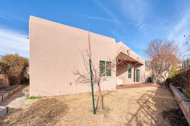 back of house featuring a patio area, fence, and stucco siding