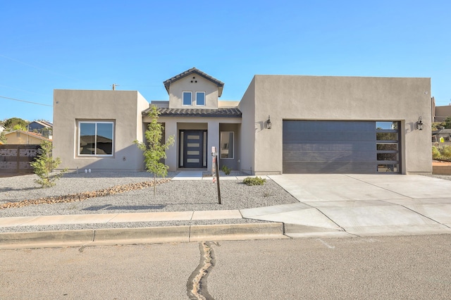 view of front of home with a garage, concrete driveway, a tile roof, and stucco siding