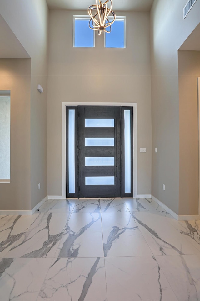 entryway featuring marble finish floor, baseboards, a high ceiling, and visible vents