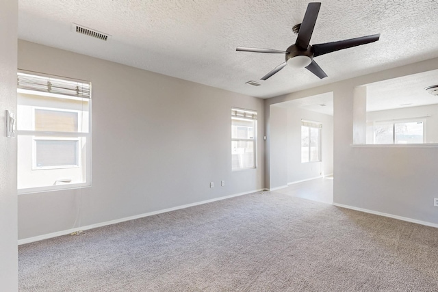 unfurnished room featuring a ceiling fan, baseboards, visible vents, a textured ceiling, and carpet flooring