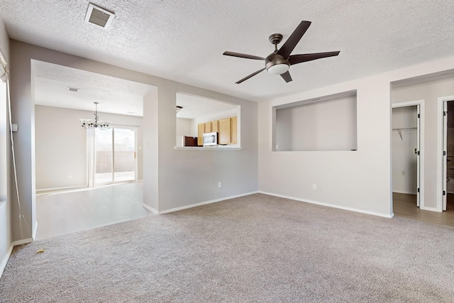 unfurnished living room featuring ceiling fan with notable chandelier, carpet, visible vents, and a textured ceiling