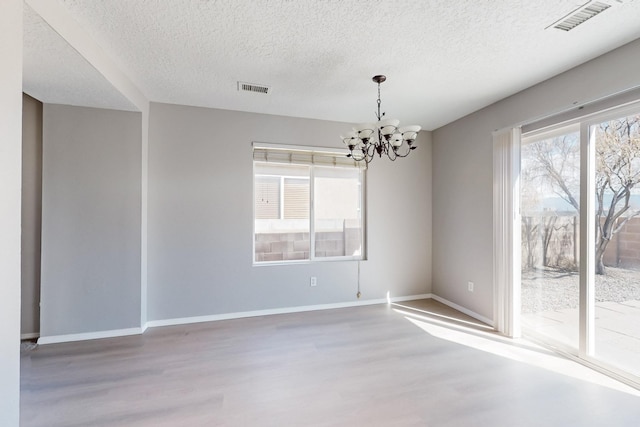 spare room with visible vents, an inviting chandelier, baseboards, and wood finished floors