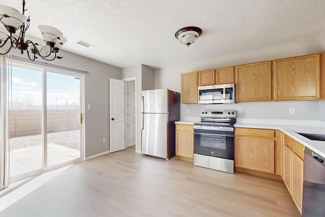 kitchen with visible vents, light wood-style flooring, light countertops, appliances with stainless steel finishes, and a notable chandelier