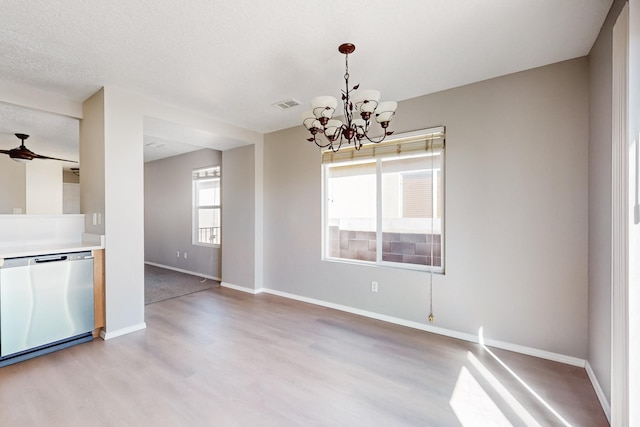 unfurnished dining area featuring visible vents, baseboards, light wood finished floors, an inviting chandelier, and a textured ceiling