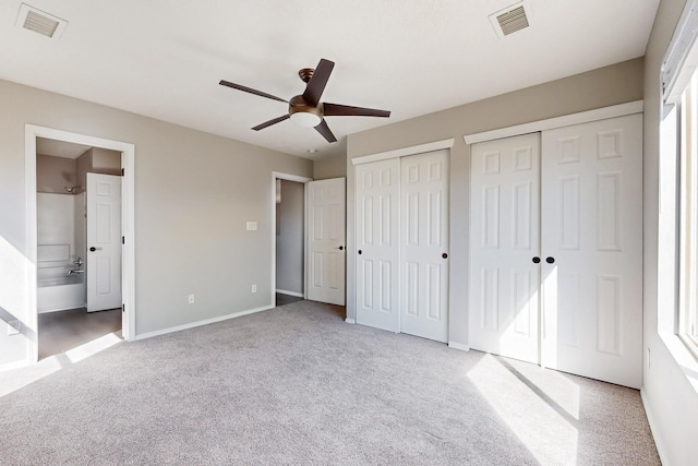 unfurnished bedroom featuring light carpet, visible vents, two closets, and baseboards