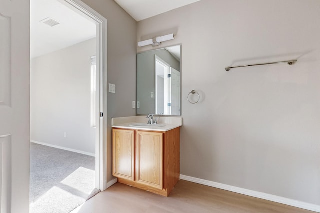 bathroom featuring visible vents, vanity, baseboards, and wood finished floors