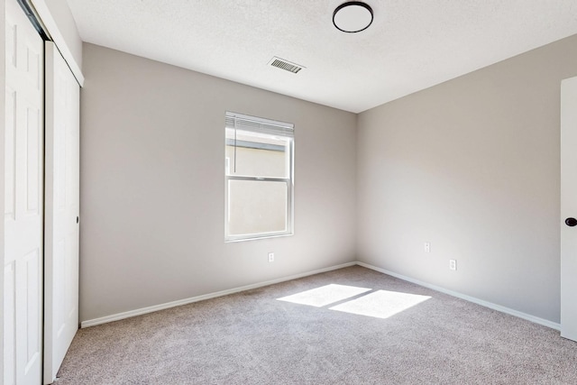 unfurnished bedroom featuring baseboards, visible vents, carpet floors, a closet, and a textured ceiling