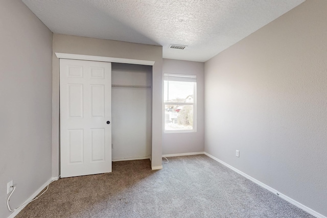 unfurnished bedroom with visible vents, baseboards, carpet floors, a closet, and a textured ceiling