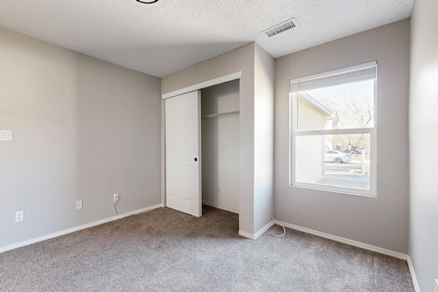 unfurnished bedroom featuring visible vents, baseboards, carpet, a closet, and a textured ceiling