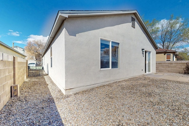 rear view of house featuring a patio area, stucco siding, and fence