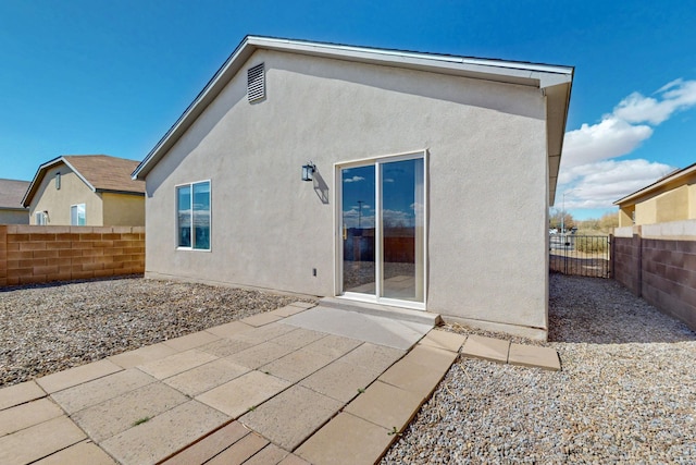 rear view of house with stucco siding, a patio area, and fence