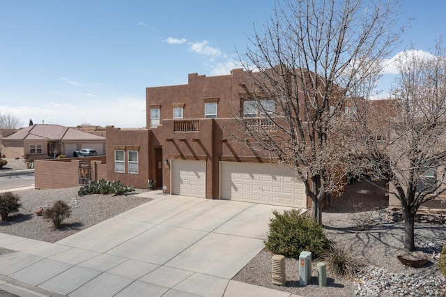 pueblo revival-style home with a garage, driveway, and stucco siding