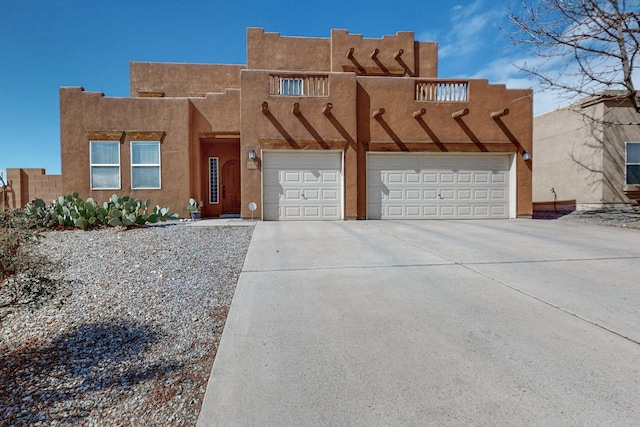 pueblo-style house with concrete driveway and stucco siding