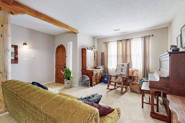 living room featuring visible vents, light carpet, beam ceiling, a textured ceiling, and baseboards