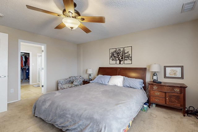 bedroom featuring visible vents, a textured ceiling, carpet floors, ceiling fan, and a spacious closet