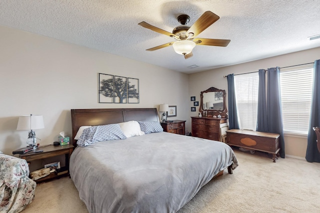 bedroom with visible vents, baseboards, ceiling fan, light carpet, and a textured ceiling