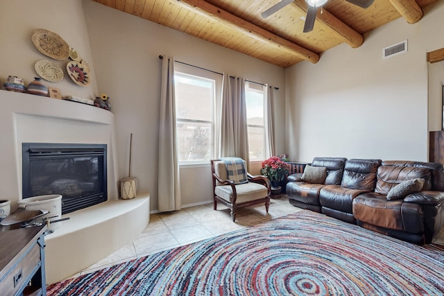 living area featuring visible vents, ceiling fan, beamed ceiling, wooden ceiling, and light tile patterned flooring