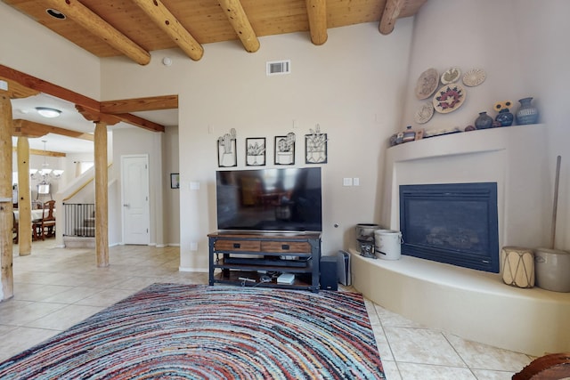 tiled living area featuring visible vents, beamed ceiling, wood ceiling, a glass covered fireplace, and a notable chandelier