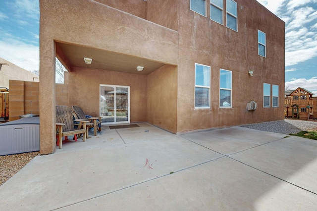 rear view of house featuring a patio area, stucco siding, and fence