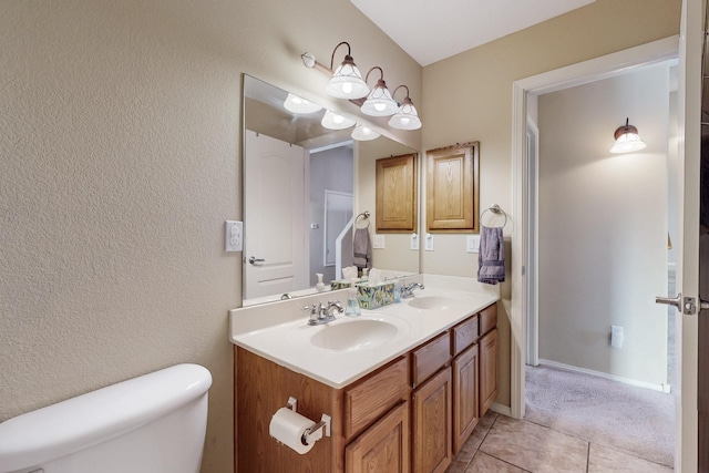 bathroom featuring double vanity, tile patterned flooring, toilet, and a sink